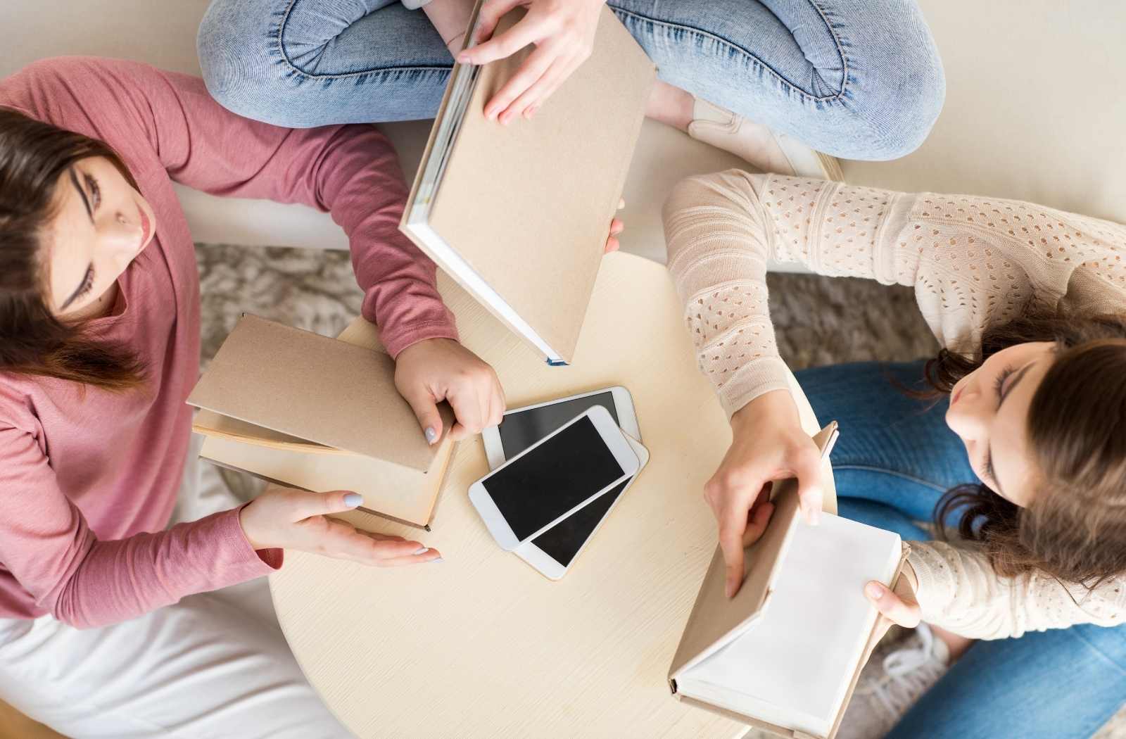 Group of young women with smart phones reading with books